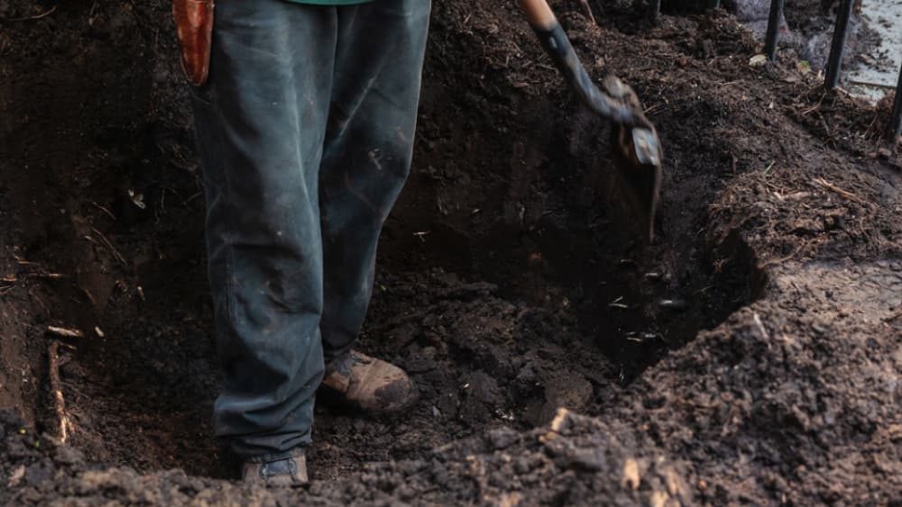 A worker digging a planting bed during Landscaping Day